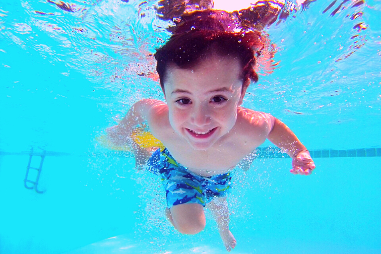 smiling boy in water with eyes open